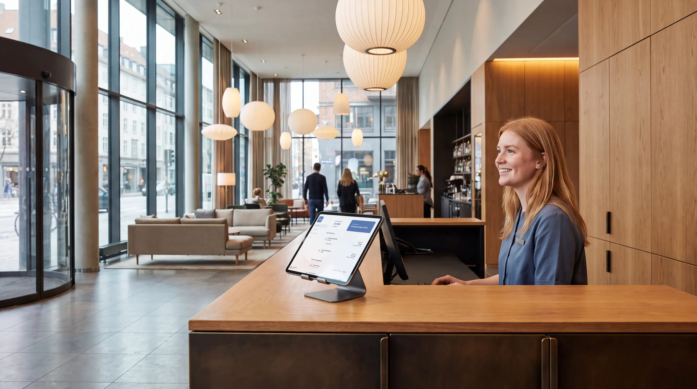 A receptionist at a modern hotel front desk with the Loyco Admin Portal on a tablet